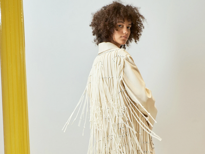 Macrame in Fashion, Black woman in cream coat with rope fringe