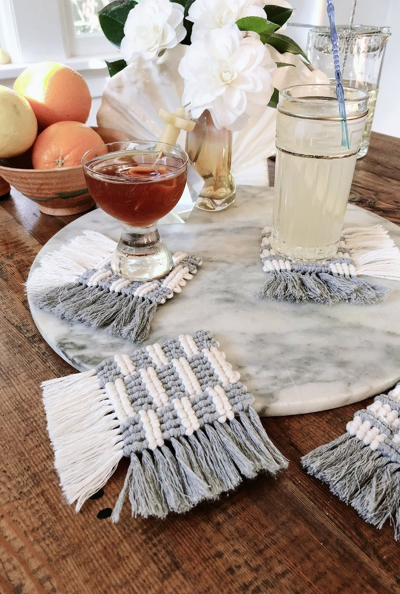 set of 4 diy macramé coasters made with 2mm string on a table with fruit, flowers & cocktails